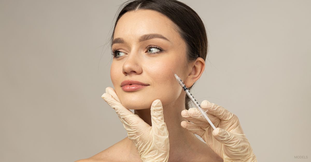 A woman is getting an injection from a person with gloves. (Models)