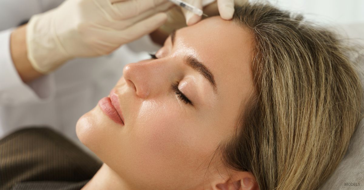 A woman getting fillers in her temple by an injector. (Models)