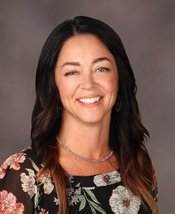 Cassandra Rommel Headshot of woman with long dark hair wearing a floral top