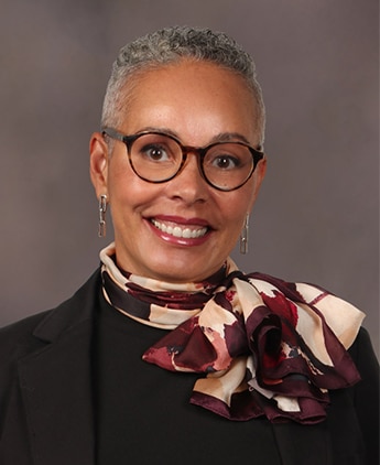 Headshot of woman with short hair wearing a scarf and a blazer.