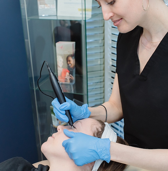 esthetician hold black pen over woman's eye