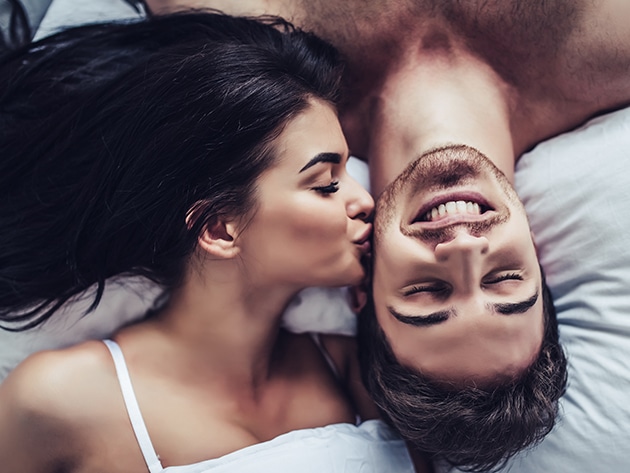 Couple laying in bed woman kissing man's cheek