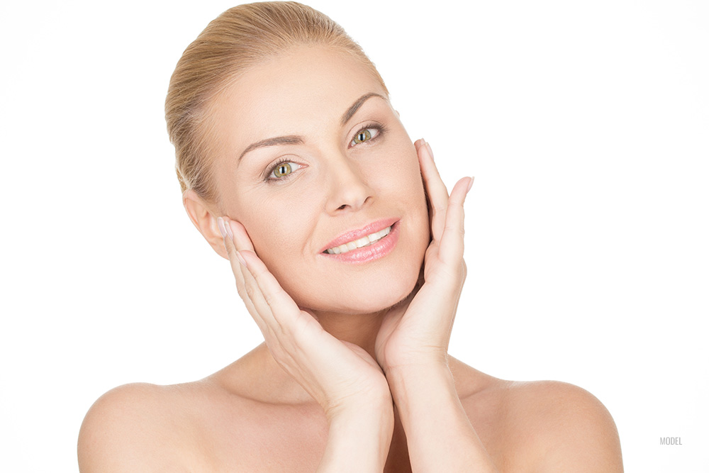 A Beautiful woman cradles her face in her hands to show her smooth skin.