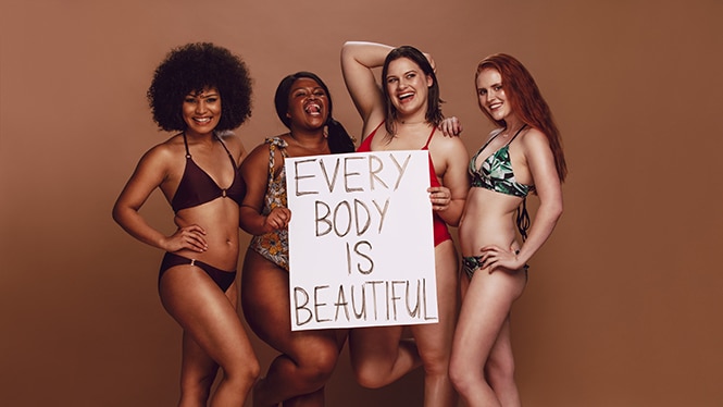 Woman of different sizes and races hole a sign that read every body is beautiful. 