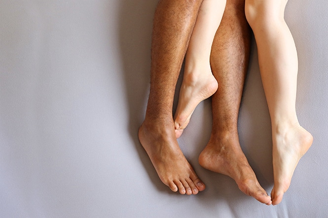 Legs intertwined in intimacy after sexual wellness treatments. 